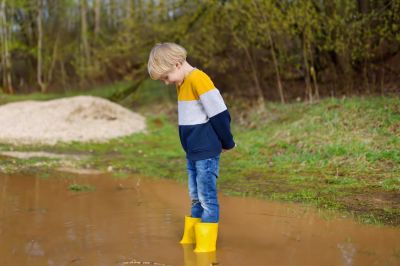 Jongen met gele laarzen in een plas water